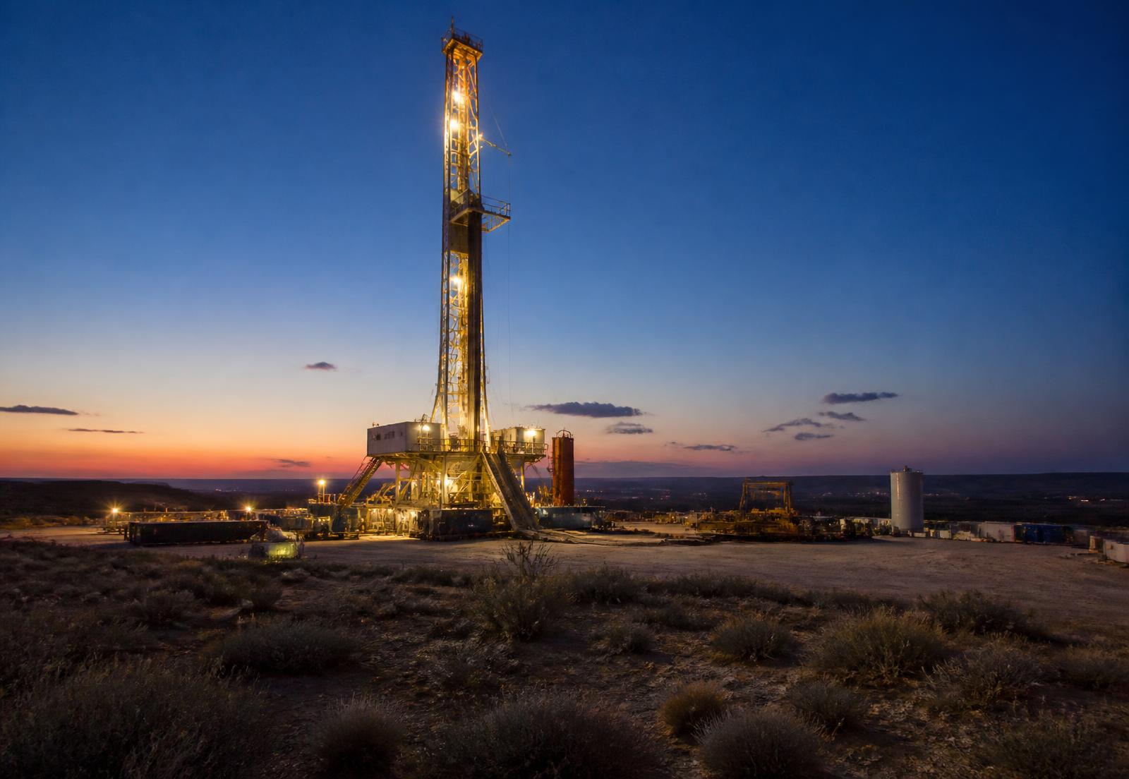 Land drilling rig lit at dusk on a West Texas pad